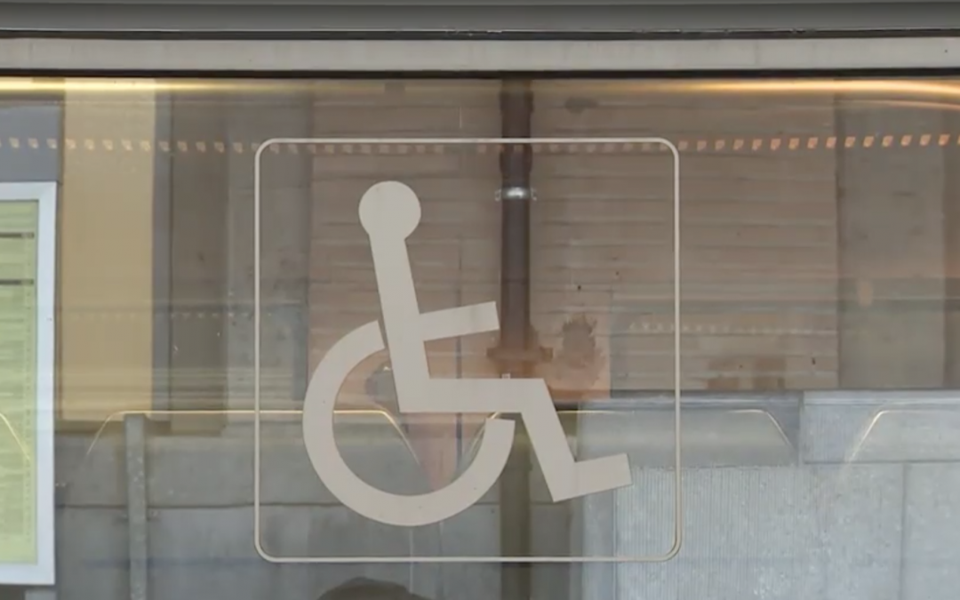 Photo d'une vitre d'un moyen de transport avec un logo "Handicap" sur la partie centrale de la vitre.