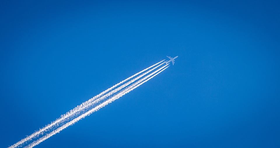 Photo d'un avion en vol dans un ciel bleu. A l'arrière de l'avion, des gouttelettes se trouvent dans le sillonnage de l'avion.