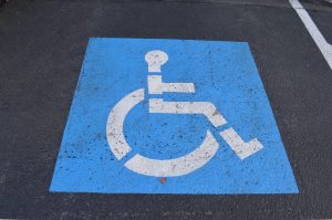 Photo prise d'un tarmac sur lequel il y a un symbole représentant une personne handicapée. Le symbole a un fond bleu avec une personne en chaise roulante, de profil, en blanc.