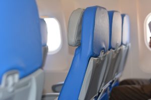 Photo de sièges d'avion prise de profil. Les sièges sont en cuir bleu et les appuis-tête en gris. Il y a, à l'arrière des sièges, des tablettes rétractables grises.