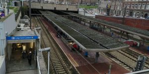 Photo prise en hauteur de la gare de Liège-Saint-Lambert sur laquelle il y a 2 quais avec un préau et des escalators.