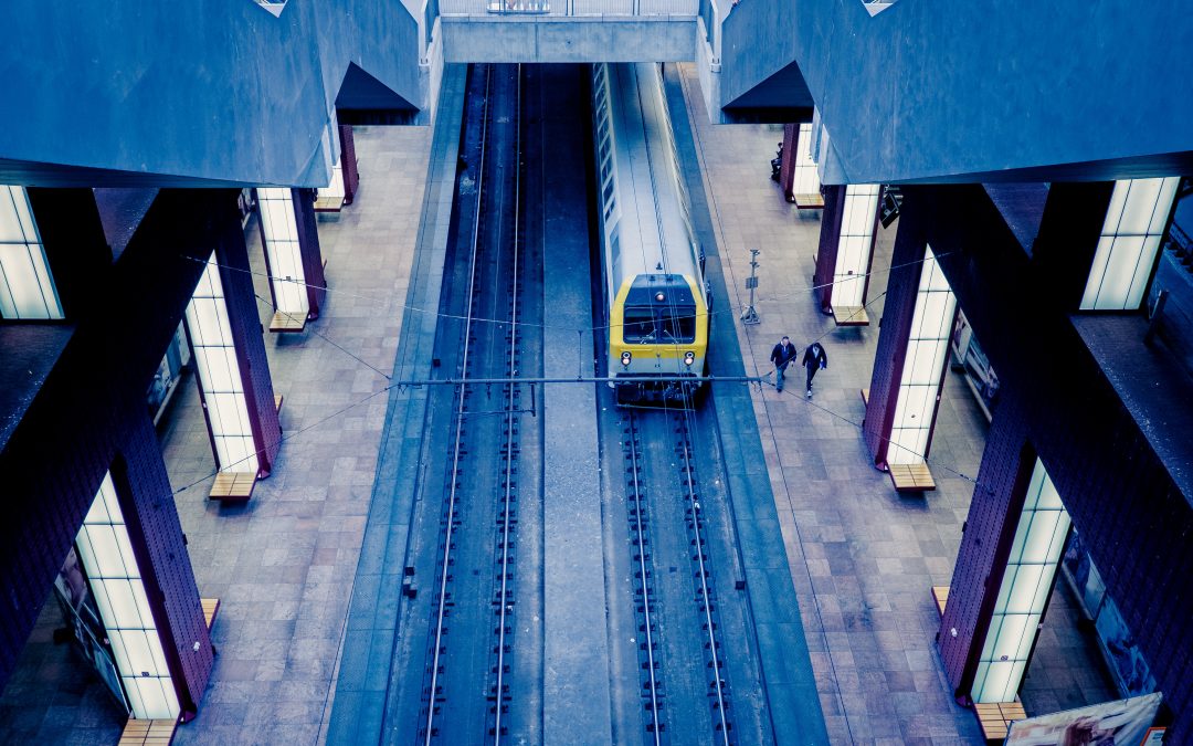 Photo d’un train prise d’en haut. On y voit un train arriver à quai. Sur ce même quai, deux personnes marchent.
